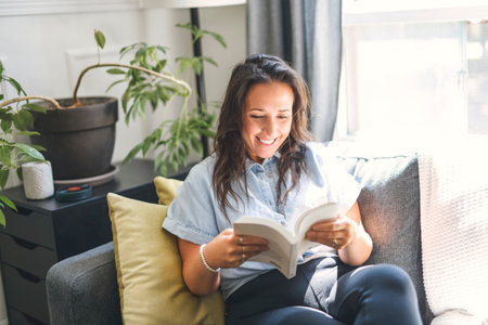 woman sitting and reading book on a sofa at home