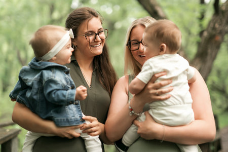 Happy family on a summer meadow. two little child with two motherの写真素材