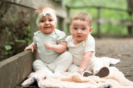 two little six months baby girls outside on meadowの写真素材