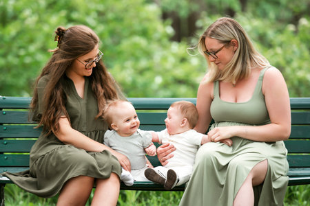 Happy family on a summer meadow. two little child with two motherの写真素材