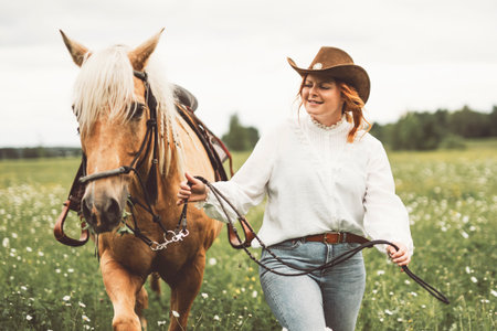 A woman is wearing a cowboy hat while riding a horse in an open fieldの写真素材