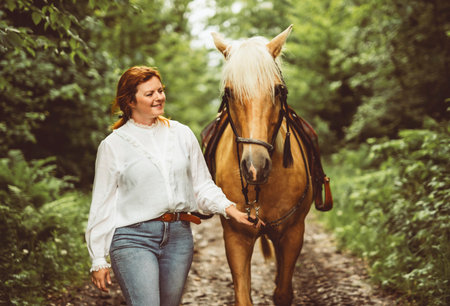 A woman is walking with a horse in a forestの写真素材