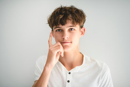 Portrait of teenage boy in casual t-shirt on light background in studio.