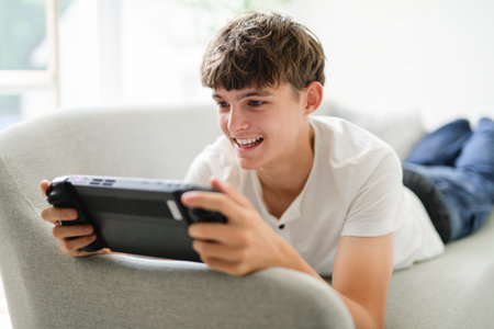 european teen play handheld console on sofaの写真素材