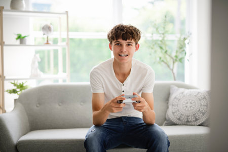 young teen sit on sofa and play video game
