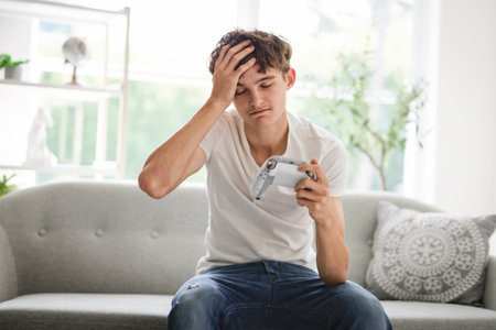 young teen sit on sofa and play video gameの写真素材