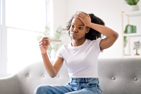 Black woman, pregnancy test and confused, nervous and waiting for results on a sofa in her homeの写真素材