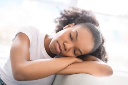 Cheerful black teen woman relaxing on sofa at home