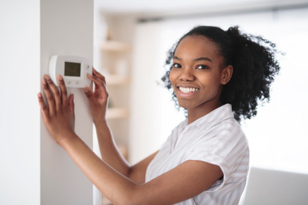 black woman using smart home system controller on wallの写真素材