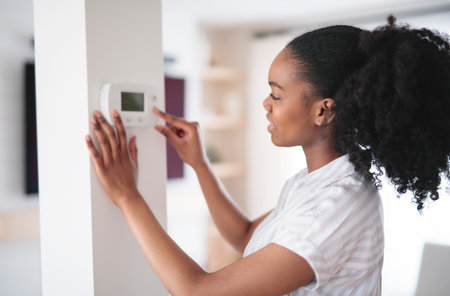 black woman using smart home system controller on wallの写真素材