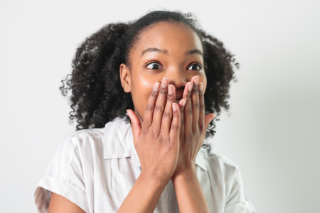 Pretty female dark skin posing isolated against white blank wall backgroundの写真素材
