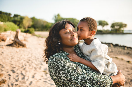 Cheerful black american mother and son against beautiful seascapeの写真素材