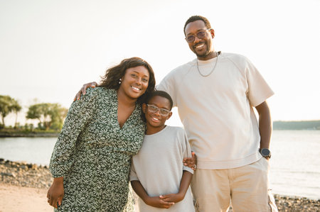 Cheerful black american mother, father and her son against beautiful seascapeの写真素材