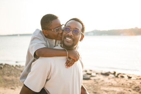 Cheerful black american father and is son against beautiful seascape