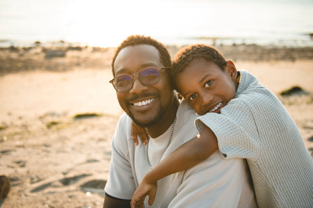 Cheerful black american father and is son against beautiful seascapeの写真素材