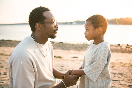 Cheerful black american father and son against beautiful seascape
