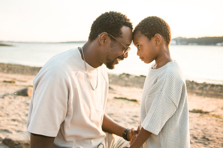 Cheerful black american father and son against beautiful seascape