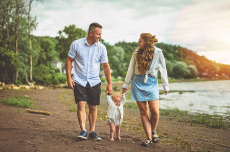 family with baby child girl at the sunset on the waterscape view from backの写真素材