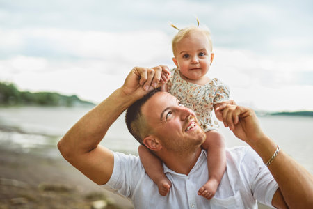 father and baby child girl at the sunset on the waterscape view from backの写真素材