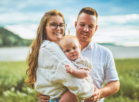 family with baby child girl at the sunset on the waterscape view from backの写真素材