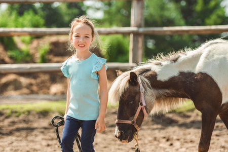 Cute little girl petting a pony in a farmの写真素材