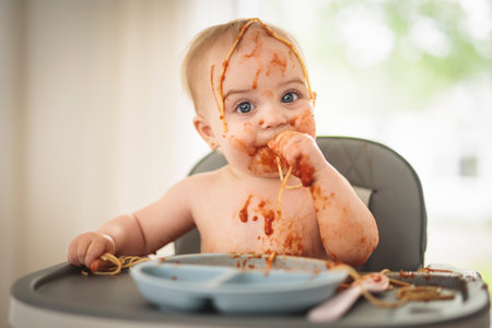 Little baby eating her dinner and making a messの写真素材