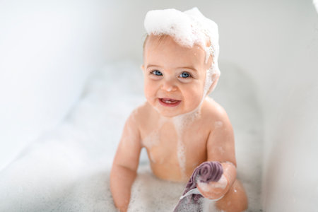 Cute little child bathing in tub at homeの写真素材
