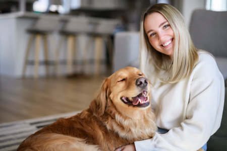 Portrait of a young woman on the livingroom with golden retriever dog indoors at home.の写真素材