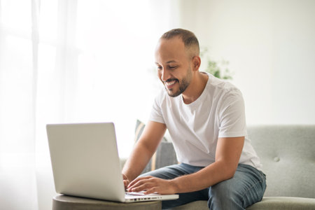 young arab man using laptop on sofa at homeの写真素材
