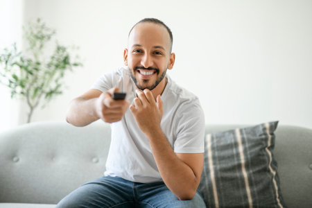 young arab man relaxing on sofa at home watching tvの写真素材