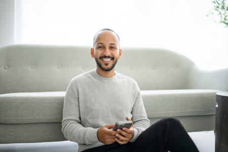 young arab man using cellphone on living room at homeの写真素材