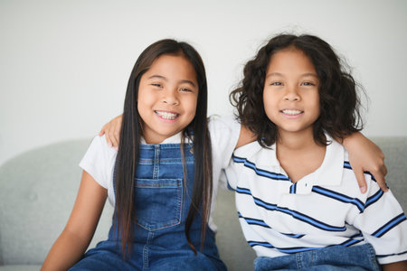 two 9 years thailand twin sit on sofa at homeの写真素材