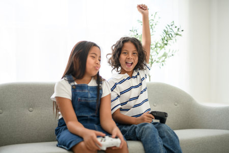 two 9 years thailand twin sit on sofa at home play video gameの写真素材