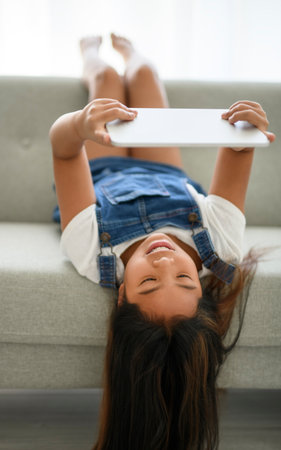 9 years thailand girl sit on sofa at home with tabletの写真素材
