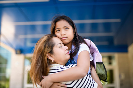 high school student girl outside on summer season with mother doing hugの写真素材