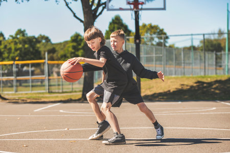 two brother in sportswear playing basketball game outsideの写真素材