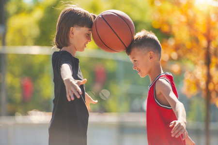 two brother in sportswear playing basketball game outsideの写真素材