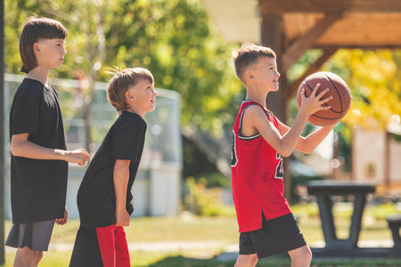 Three brother in sportswear playing basketball game outsideの写真素材