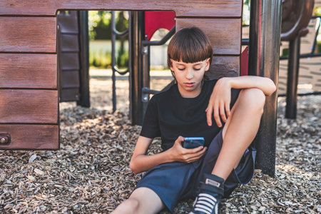 Portrait of teen using cellphone on school playgroundの写真素材