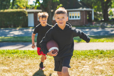 brother playing American football. Kids play football in sunny summer park.の写真素材
