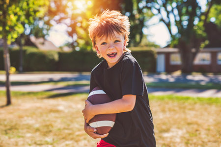 child boy playing American football. Kid play football in sunny summer park.の写真素材