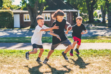 brother playing American football. Kids play football in sunny summer park.の写真素材
