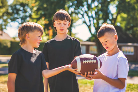 brother playing American football. Kids play football in sunny summer park.の写真素材