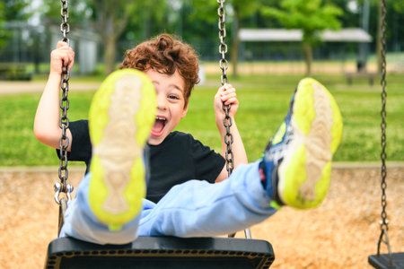 Happy 5 years old boy on a swing. Happy kid on playgroundの写真素材