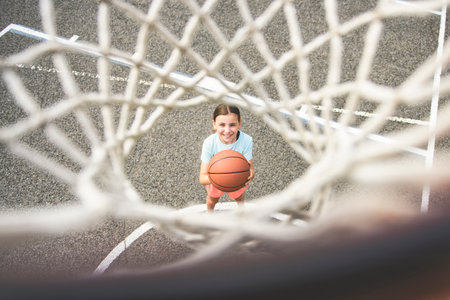girl child in sportswear playing basketball game