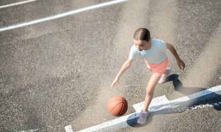 girl child in sportswear playing basketball gameの写真素材