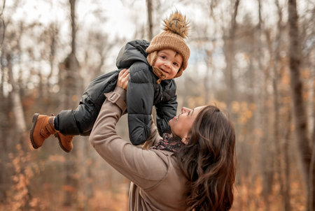 Joyful mother and his little baby. mother and child have fun, laugh and enjoy nature outdoors at autumn park.の写真素材