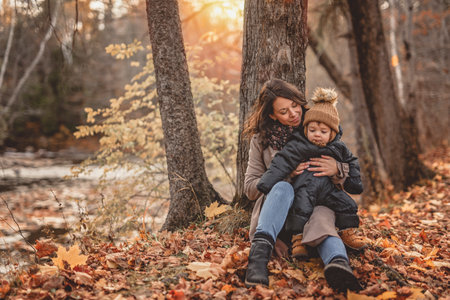 Joyful mother and his little baby. mother and child have fun, laugh and enjoy nature outdoors at autumn park.の写真素材