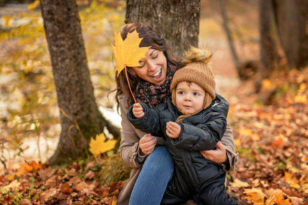 Joyful mother and his little baby. mother and child have fun, laugh and enjoy nature outdoors at autumn park.の写真素材