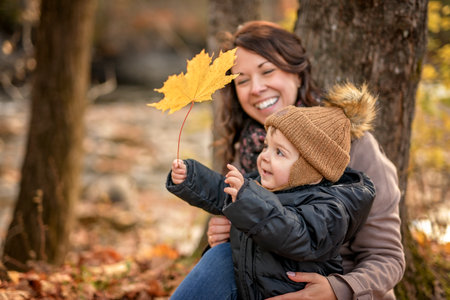 Joyful mother and his little baby. mother and child have fun, laugh and enjoy nature outdoors at autumn park.の写真素材